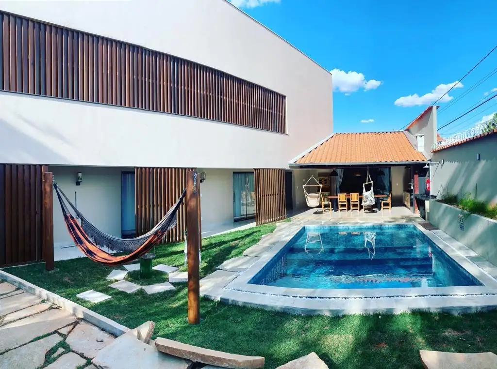 Jardim com redes penduradas, piscina e área gourmet ao fundo do AYVÚ Recanto